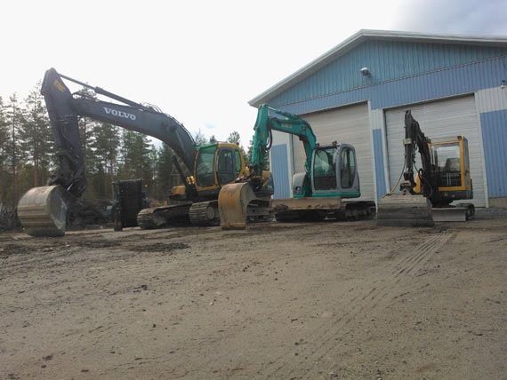 Kolme kaivinkonetta varastorakennuksen edessä Jyväskylässä valmiina maanrakennustöihin.